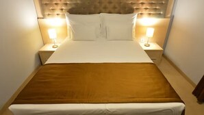 Un lit avec une tête de lit marron, une literie blanche et deux lampes de chevet.