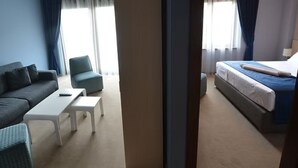 Una habitació d'hotel amb un sofà, una taula petita, un llit i una cadira.