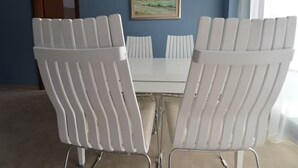 Un salón de conferencias con una mesa y sillas blancas, un cuadro en la pared y una puerta.