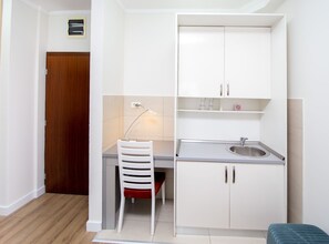 A compact kitchenette with a sink, cabinets, and a chair.