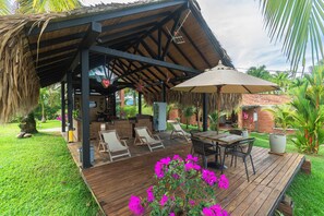 A wooden deck with outdoor furniture, a covered seating area, and a garden with flowers. - HOTEL CAMPESTRE LA MANOLA  (Puerto Triunfo)