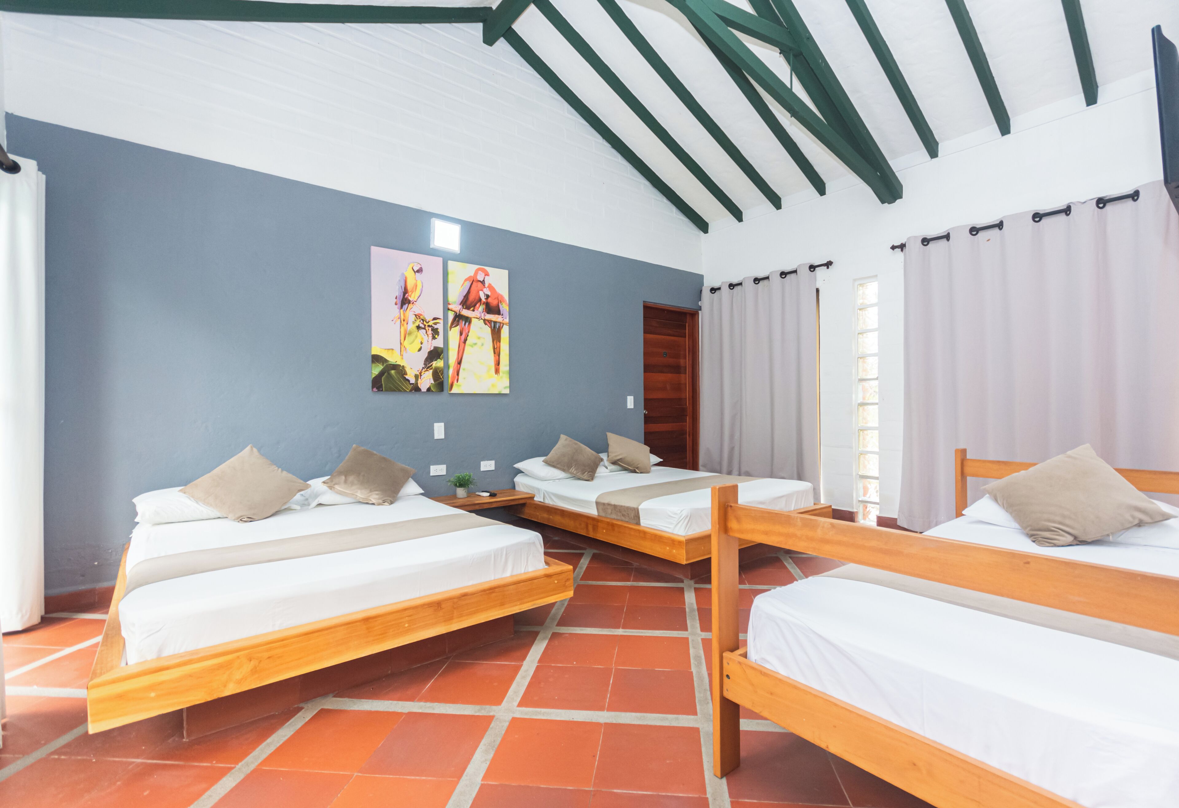 Una habitación con tres camas de madera, una pared azul y techo de madera.
