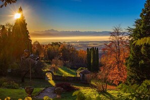 Un jardín con senderos, un pabellón y vistas a montañas lejanas.