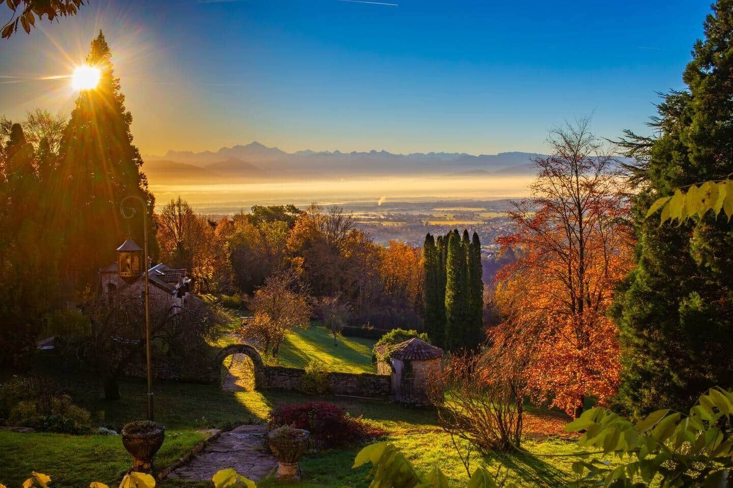 Un jardín con un pabellón, un sendero de piedra y vistas a montañas distantes.