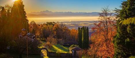 A garden with a gazebo, stone pathway, and a view of distant mountains.