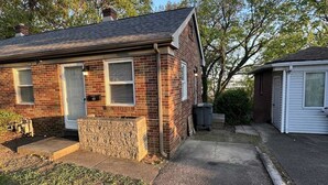 A single-story brick house with a front porch, a small stone retaining wall, and a paved driveway. - Deaconess Gateway 3 miles, Quiet, Open, 1BDRM, Private Parking & More! (Evansville)