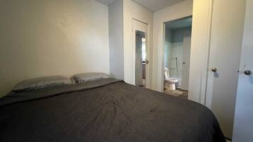 Ein Schlafzimmer mit einem Bett, einer Tür zu einem Badezimmer und einer sichtbaren Toilette.