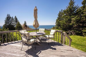 A wooden deck with a table and chairs, overlooking a body of water and surrounded by trees. - Cliffside Oceanfront Bit of Heaven (Murray River)