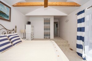 A bedroom with a bed, a dresser, a radiator, and a door leading to another room. - Cliffside Oceanfront Bit of Heaven (Murray River)
