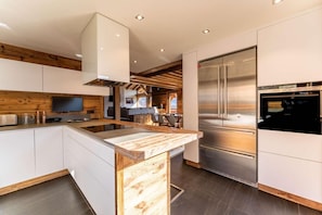 A modern kitchen with a central island, stainless steel appliances, and a wooden accent wall. - Chalet, 350m from shops, 2nd floor, terrace, fireplace or stove, parking, tv, 200m², Combloux (Combloux)