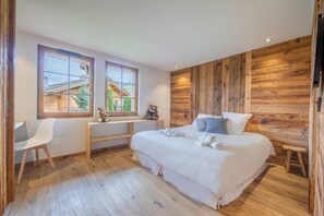 A bedroom with a wooden wall, a bed, a desk, and a chair. - Chalet, 350m from shops, 2nd floor, terrace, fireplace or stove, parking, tv, 200m², Combloux (Combloux)