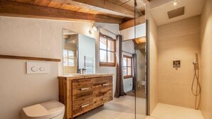 Ein modernes Badezimmer mit einem Holzwaschtisch, einer Toilette und einer gläsernen Dusche.