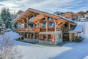 A multi-story wooden chalet with large windows and a balcony, surrounded by snow. - Chalet, 350m from shops, 2nd floor, terrace, fireplace or stove, parking, tv, 200m², Combloux (Combloux)