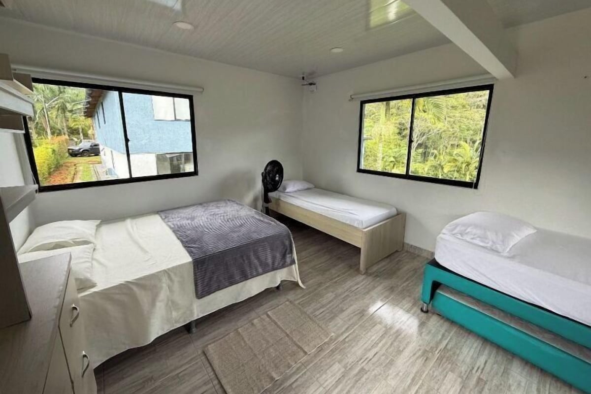 Una habitación con dos camas, un escritorio y un ventanal con vistas a zonas verdes.