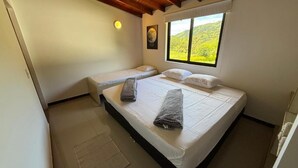 A bedroom with two beds, a window with a view, a ceiling fan, and a wall-mounted light. - Hotel Selva Cristal (San Carlos)