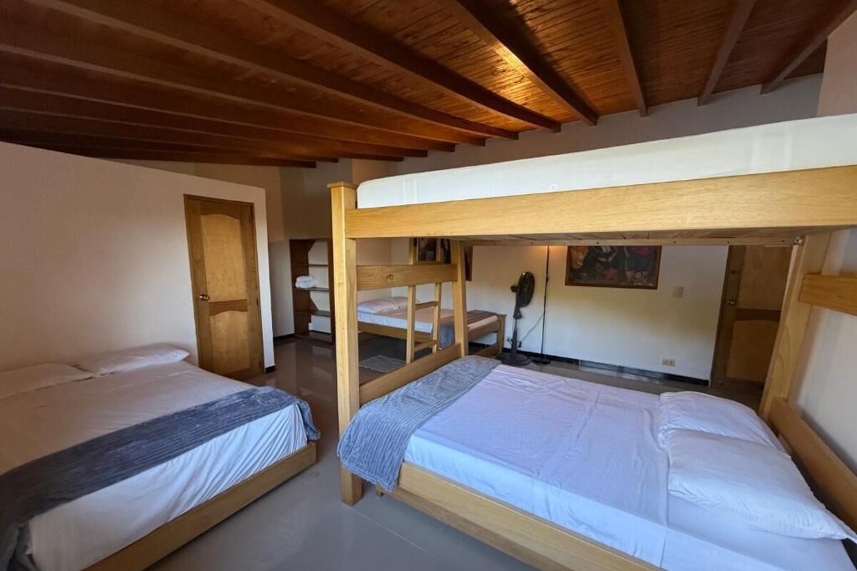 Una habitación con dos literas, vigas de madera en el techo y una puerta al fondo.