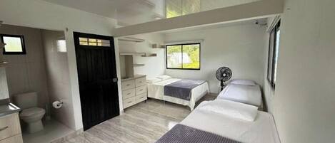 Ein Schlafzimmer mit Bett, Kommode, Ventilator und Fenster.