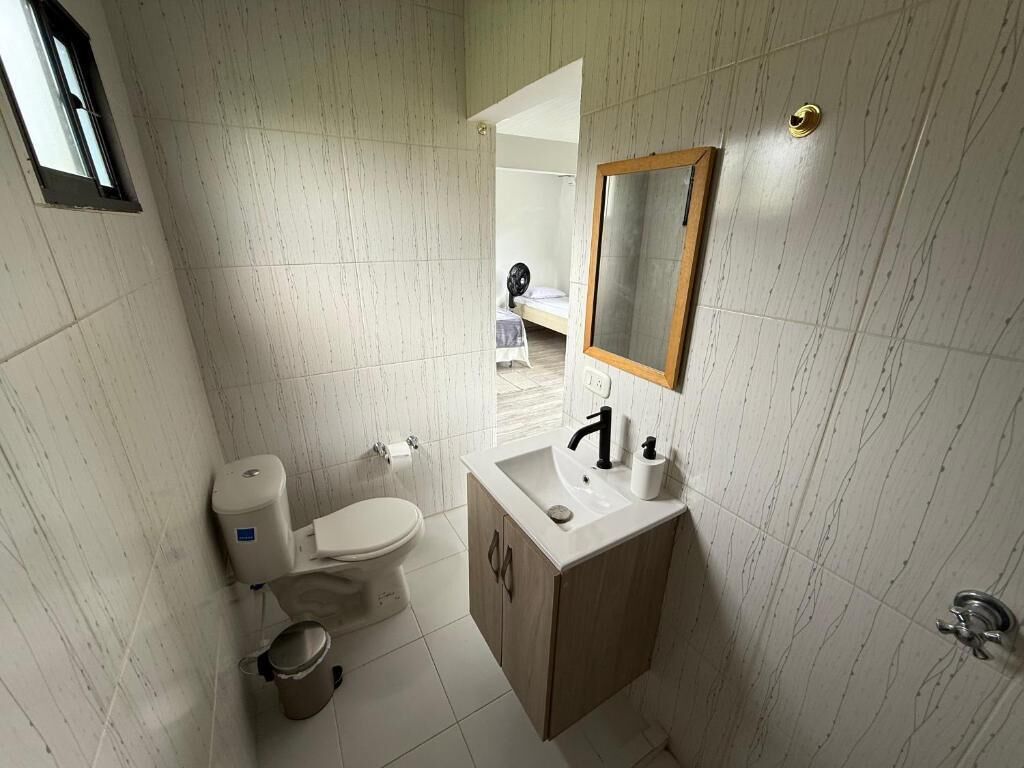 Et lille badeværelse med toilet, vask og spejl.