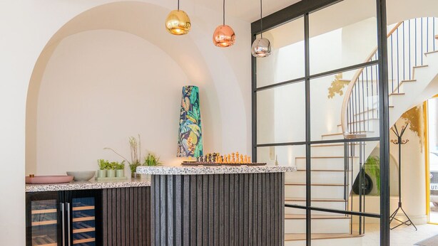 A modern kitchen with a central island, pendant lights, and a staircase leading to an upper level. - Chic Devon Designer Oasis with hot tub (Kingsbridge)
