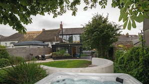 A modern house with a hot tub in the yard, surrounded by greenery. - Chic Devon Designer Oasis with hot tub (Kingsbridge)