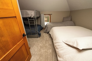 Une chambre de dortoir avec des lits superposés, une fenêtre avec des rideaux et une porte.