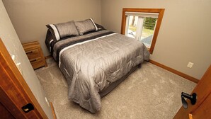Un dormitorio con una cama, una mesita de noche, una ventana y una puerta.