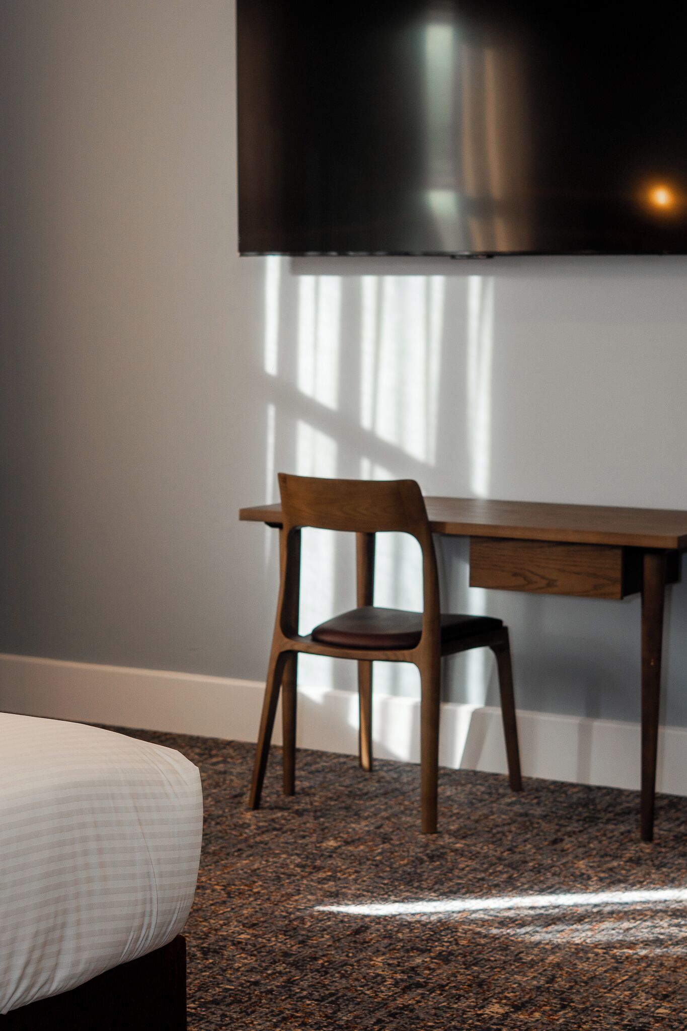 A bedroom with a bed, a wooden desk, and a chair.