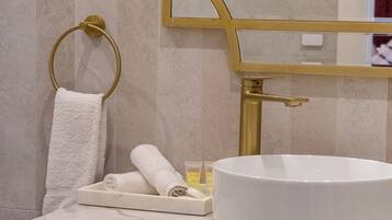 Un baño con un lavabo blanco redondo, un toallero dorado y un espejo con marco dorado.