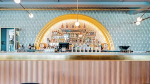 A bar area with a wooden counter, a patterned wall, and a large arched display of bottles.