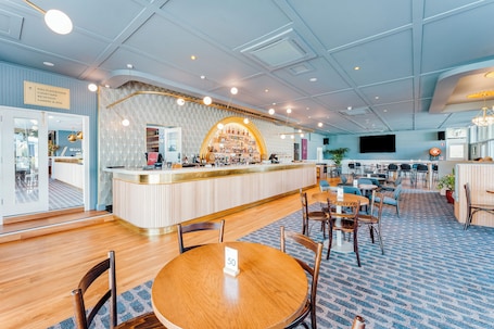A hotel lobby with a bar area, seating arrangements, and a sign indicating a kids playground and gaming area.. Kincraig Hotel