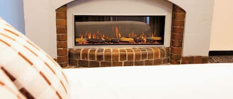 A fireplace with a brick surround and a white mantel, set against a wall.