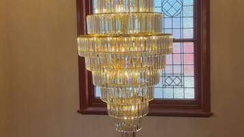 A multi-tiered crystal chandelier hanging from a ceiling with a geometric pattern.