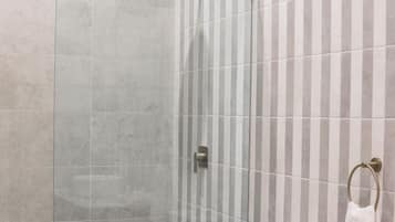 Un baño moderno con ducha de vidrio, inodoro y tocador con encimera de mármol.
