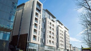 A multi-story hotel with a modern design, featuring large windows and a prominent entrance. - Modern 2BR Apartment w/ Balcony | Sleeps 6 (Merseyside)