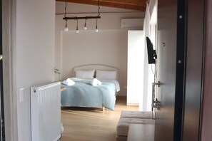 A bedroom with a bed, bedside table, and a radiator. - Cozy Studio with a Heart-Stealing View (Gerakas)