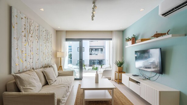 Ein modernes Wohnzimmer mit einer Couch, einem Couchtisch, einem Fernseher und dekorativen Regalen.