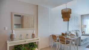 Ein modernes Wohnzimmer mit einem weißen Konsolentisch, Korbstühlen, einer Couch und einem großen Spiegel.