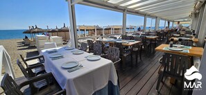 An outdoor dining area with tables set for guests, overlooking the beach. - Marina 2 Suites | Fuengirola (Fuengirola)