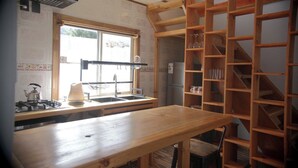 A kitchen with a wooden table, a gas stove, a kettle, and a sink. - Apart Hotel Plaza Araucaria, Individual Apartment 5 p. Mañihuales, Carretera Austral (Villa Mañihuales)