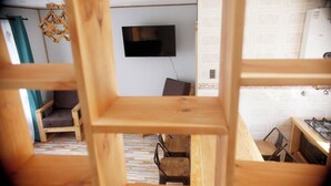 A room with a TV mounted on the wall, a dining table with chairs, and a kitchen area with a stove. - Apart Hotel Plaza Araucaria, Individual Apartment 5 p. Mañihuales, Carretera Austral (Villa Mañihuales)