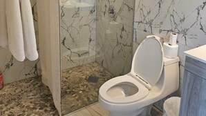 Ein Badezimmer mit Duschkabine, Toilette und Wand mit Marmoroptik.