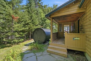 A wooden cabin with a porch and a large barrel. - Lake View House with Hot Tub, Sauna and Game Loft (Woodstock)