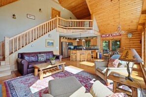 A spacious living area with a wooden staircase, a kitchen, and a dining area.