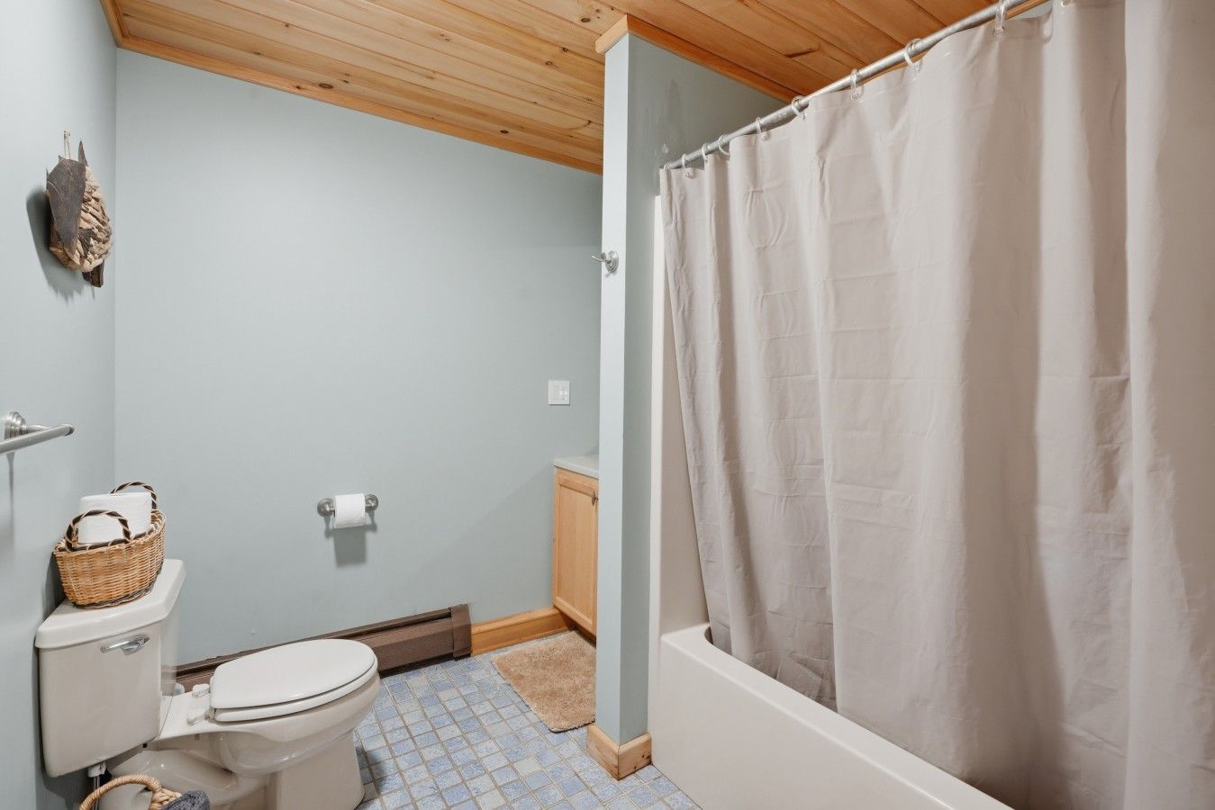 A bathroom with a toilet, a shower curtain, and a tiled floor.