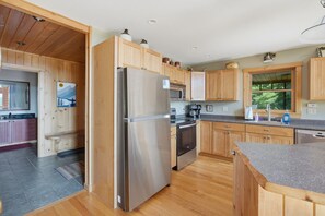 A modern kitchen with wooden cabinets, stainless steel appliances, and a granite countertop.