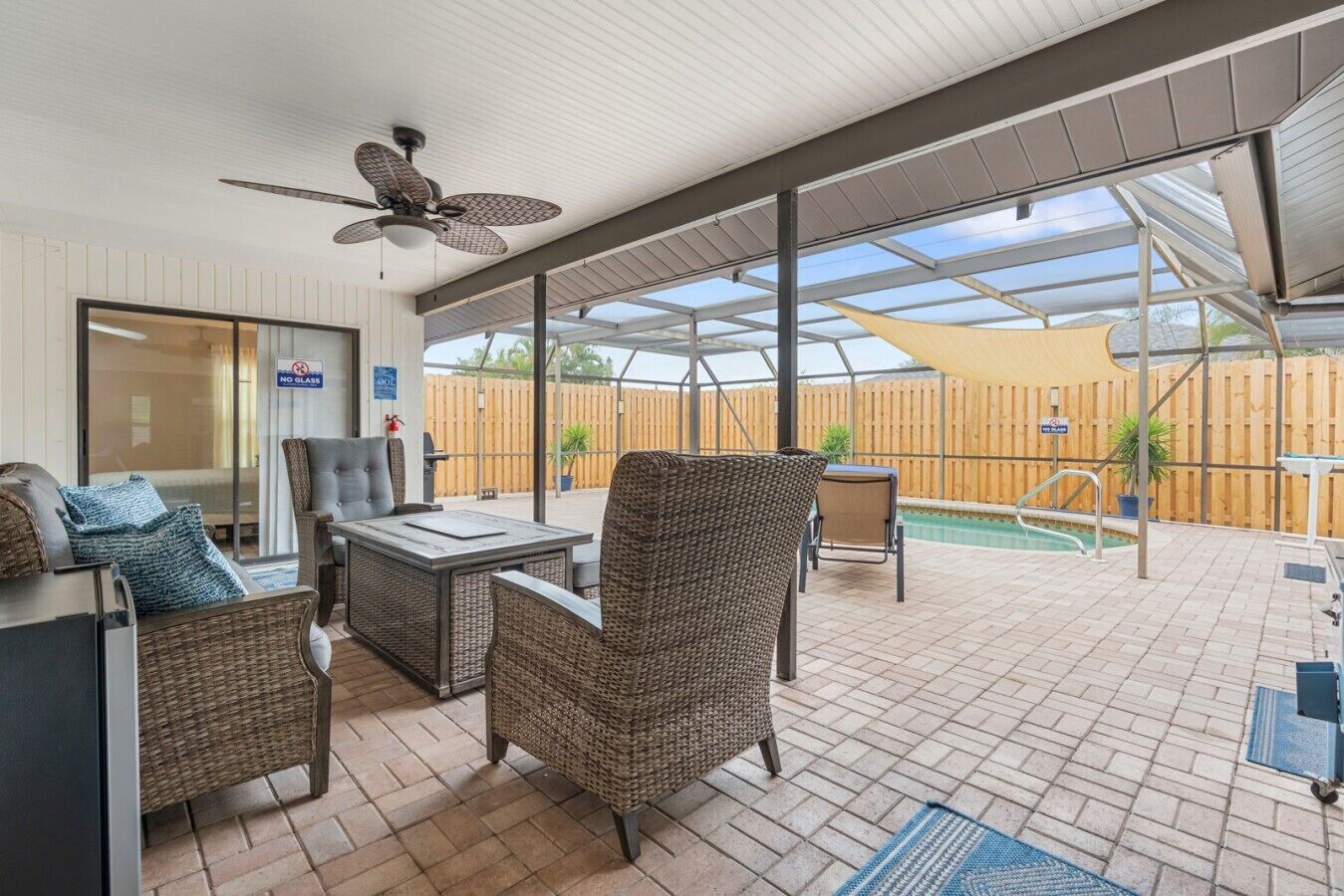 Ein Terrassenbereich im Freien mit Korbmöbeln, einem Deckenventilator und einem Pool.