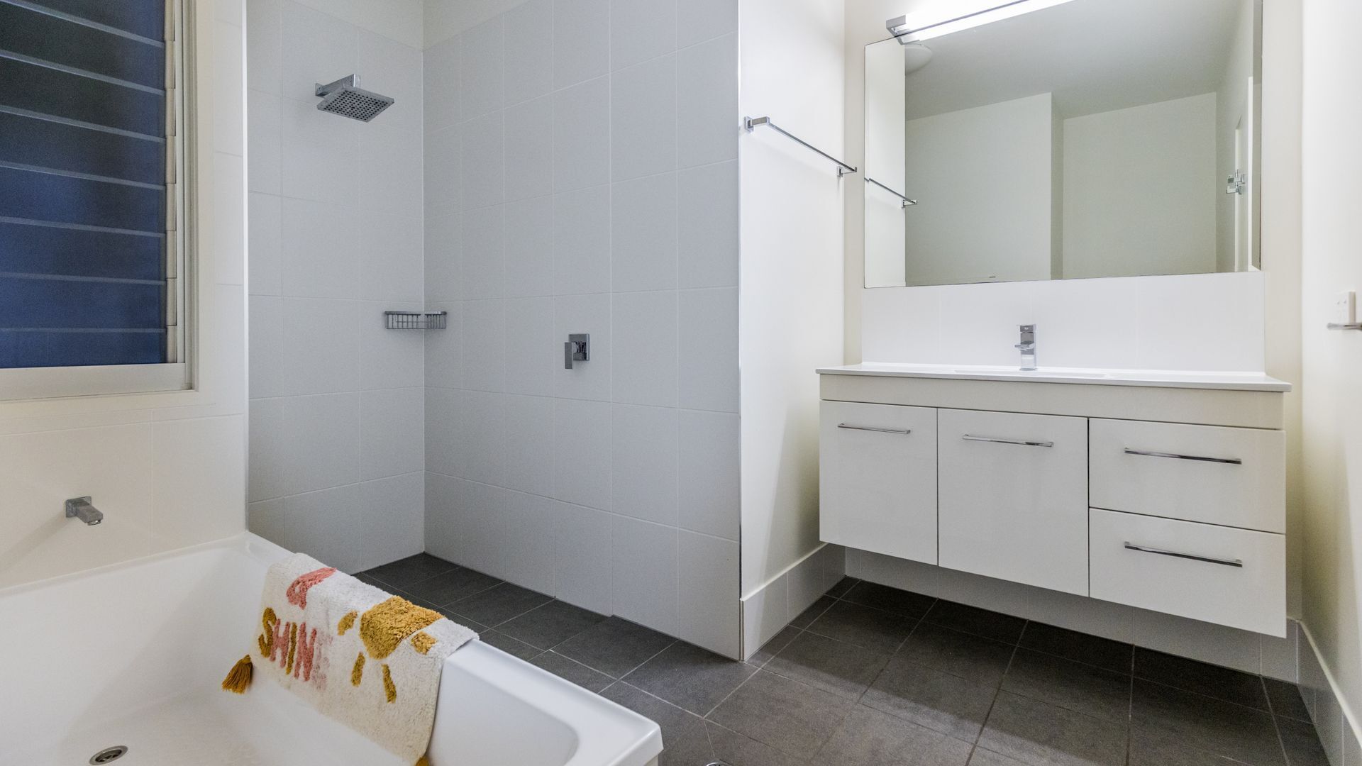 Un baño con bañera, ducha y tocador con cajones.
