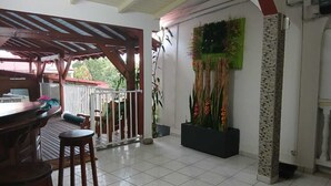 A covered outdoor area with a bar and stools, a staircase, and a wall decorated with plants. - MAGNIFICENT FURNISHED VILLA WITH SWIMMING POOL AND MOUNTAIN VIEW (Petit-Bourg)