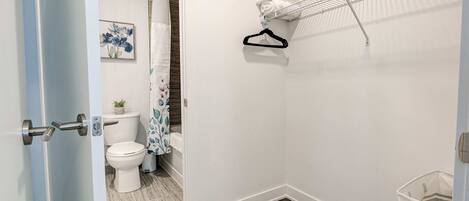 A bathroom with a toilet, shower curtain, and a towel rack.