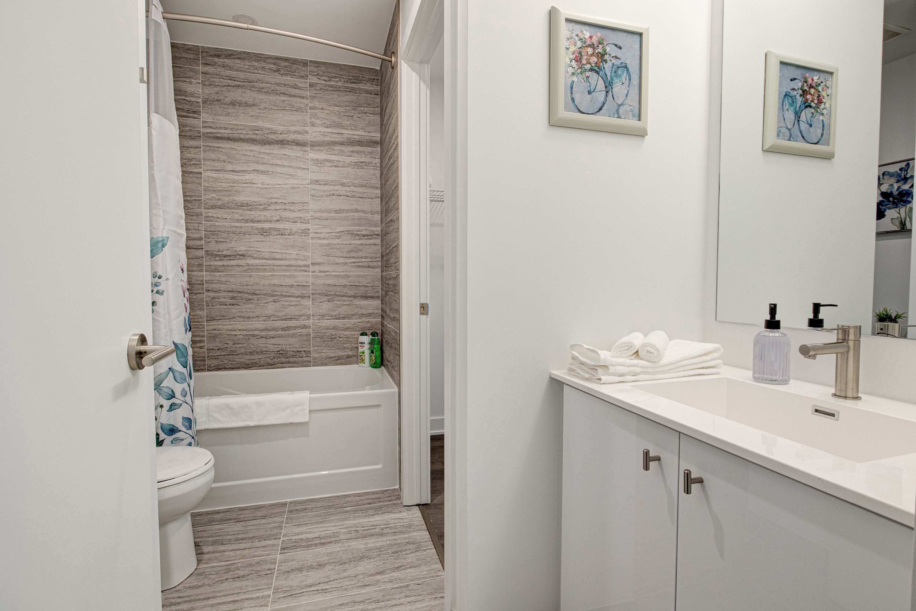 Een moderne badkamer met een douche, toilet en wastafel, met een betegelde vloer en een witte badkamerkast.
